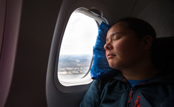 A person using a stuffed Pocket Travel Pillow in a plane.